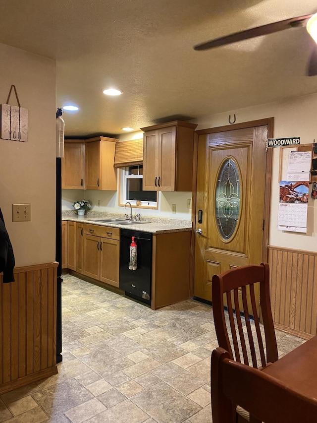 kitchen featuring sink, wooden walls, and dishwasher