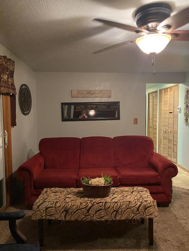 carpeted living room featuring a textured ceiling and ceiling fan