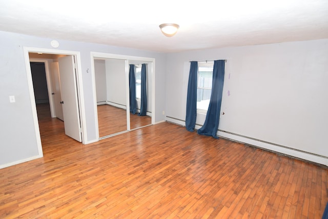 empty room featuring hardwood / wood-style floors and a baseboard radiator