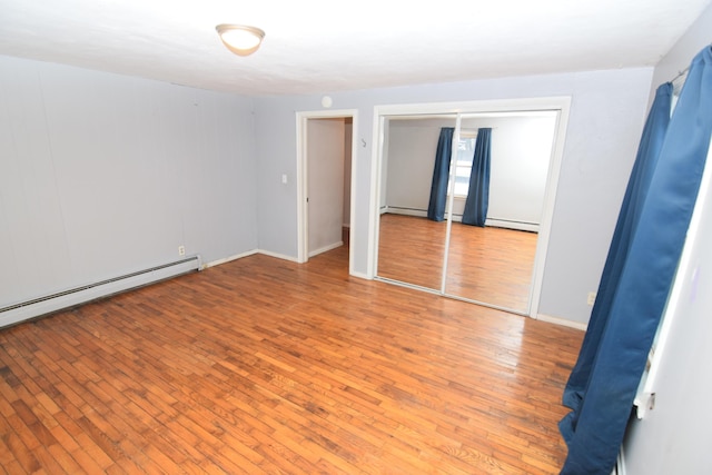 empty room featuring a baseboard radiator and light hardwood / wood-style flooring