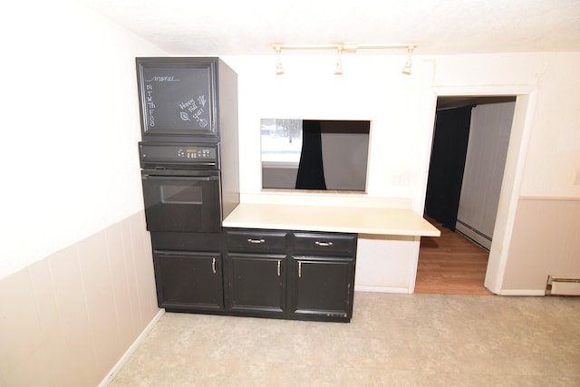 kitchen featuring baseboard heating, wood walls, and oven