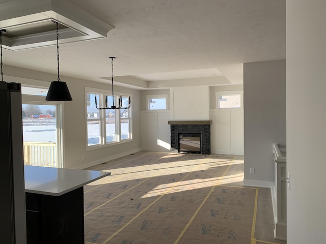 unfurnished living room with a fireplace, a chandelier, and a healthy amount of sunlight