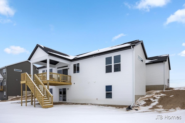 snow covered back of property featuring a deck