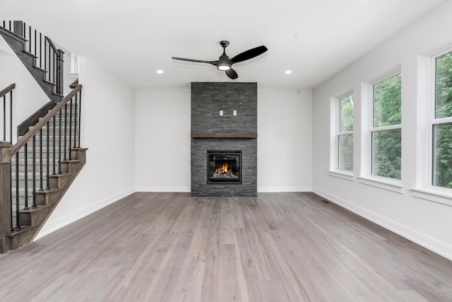 unfurnished living room with ceiling fan, a fireplace, and light hardwood / wood-style flooring