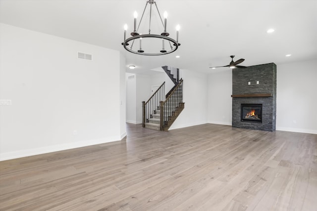 unfurnished living room with a stone fireplace, ceiling fan, and light hardwood / wood-style floors