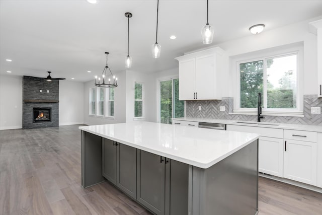 kitchen featuring a large island, sink, white cabinets, and decorative light fixtures