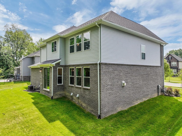 back of property featuring a lawn and central air condition unit