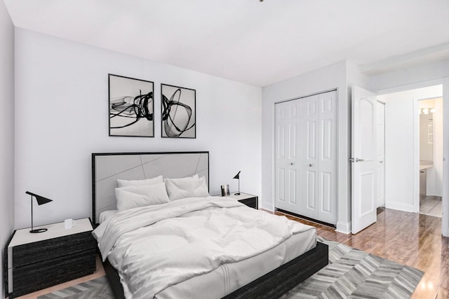 bedroom featuring hardwood / wood-style flooring, ensuite bath, and a closet