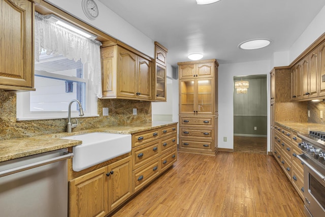 kitchen with light stone counters, sink, decorative backsplash, and appliances with stainless steel finishes