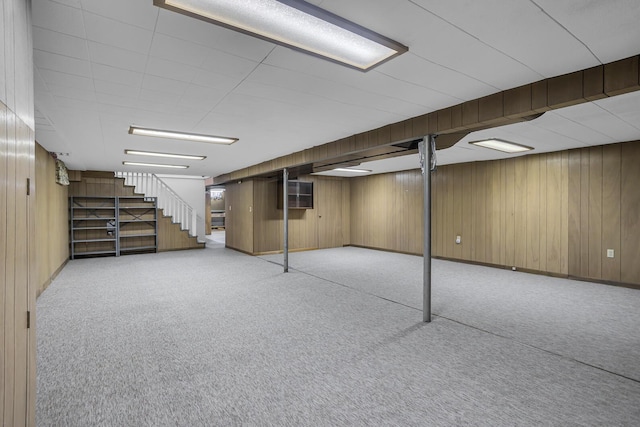 basement featuring light colored carpet and wood walls