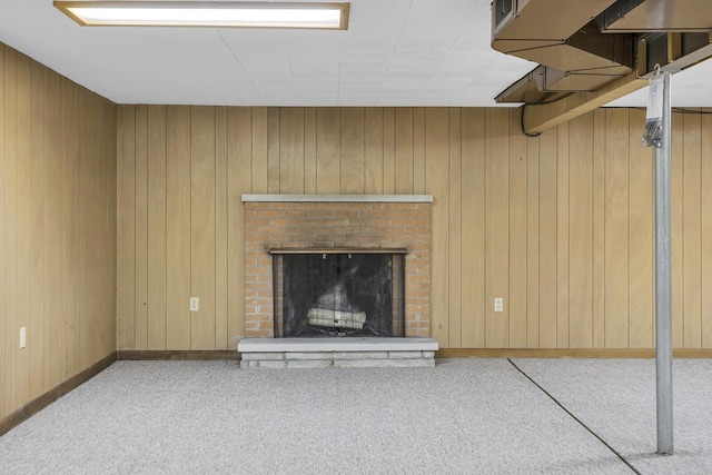 unfurnished living room with a brick fireplace, carpet flooring, and wooden walls