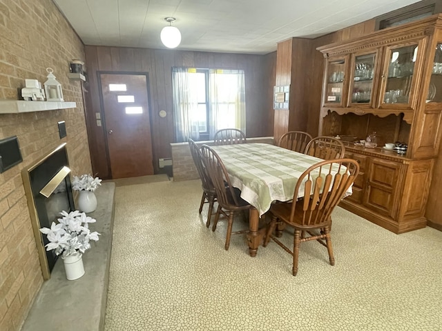 dining room with brick wall, wooden walls, and a fireplace