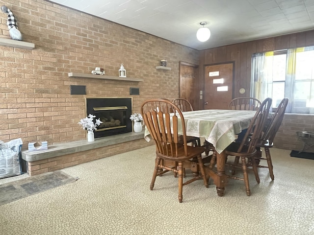 dining room featuring wooden walls, brick wall, and a fireplace