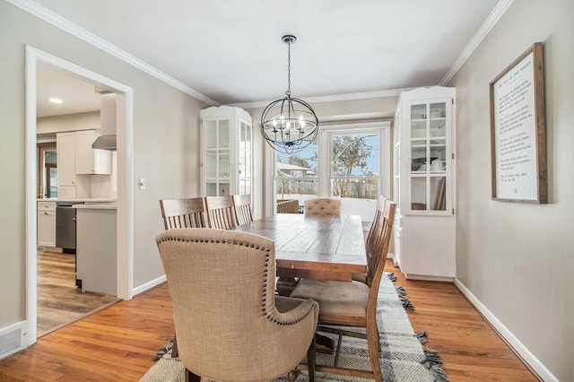 dining area featuring crown molding, a notable chandelier, and light hardwood / wood-style flooring