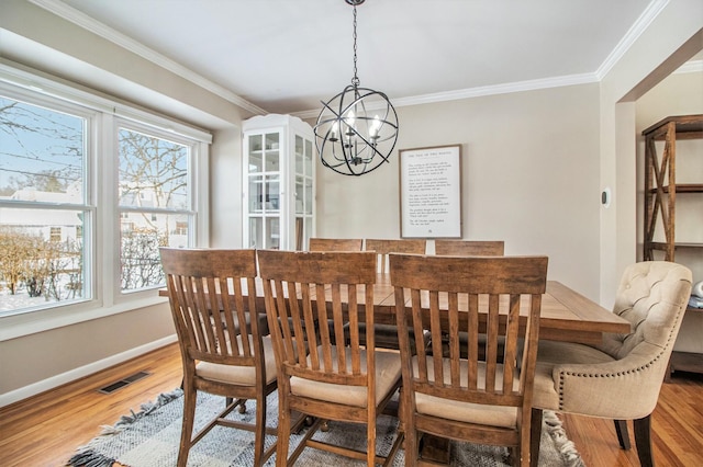 dining space with an inviting chandelier, crown molding, and hardwood / wood-style flooring