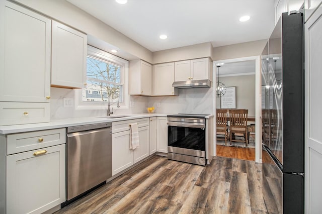 kitchen with stainless steel appliances, white cabinetry, sink, and dark hardwood / wood-style floors