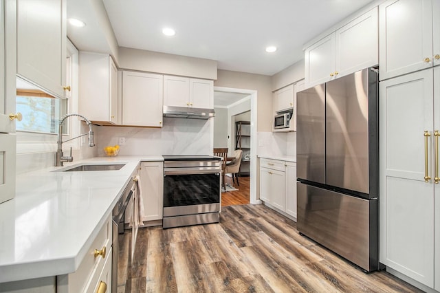 kitchen with stainless steel appliances, white cabinetry, backsplash, and sink