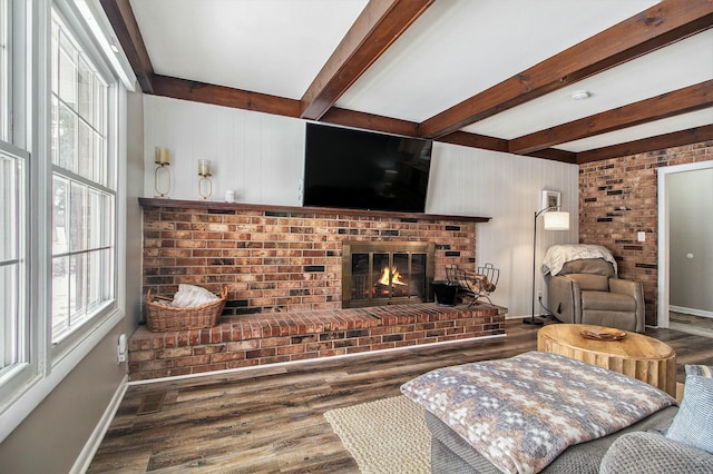 living room with beam ceiling, a brick fireplace, and wood-type flooring