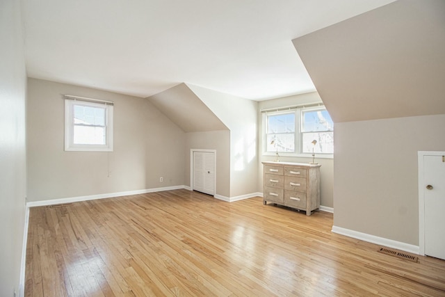 additional living space featuring vaulted ceiling, light hardwood / wood-style floors, and a healthy amount of sunlight