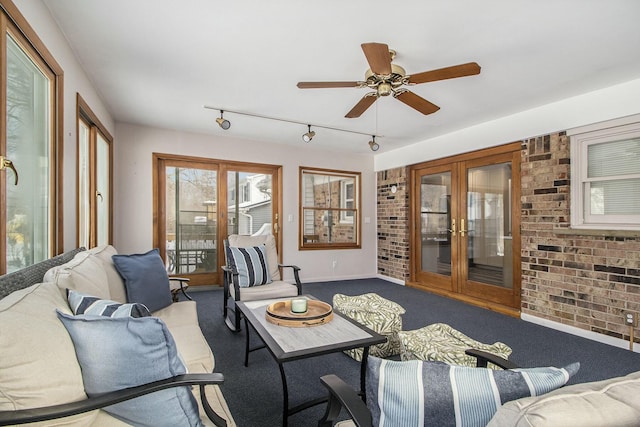 carpeted living room with ceiling fan, french doors, and brick wall