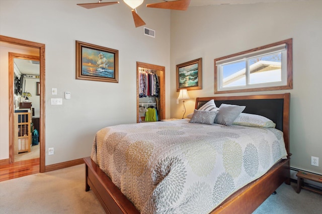 bedroom featuring light colored carpet, ceiling fan, a spacious closet, and a closet