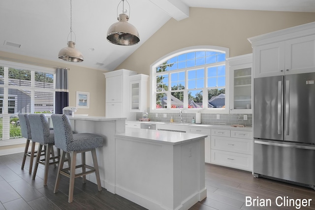 kitchen featuring white cabinetry, tasteful backsplash, stainless steel refrigerator, a kitchen island, and pendant lighting