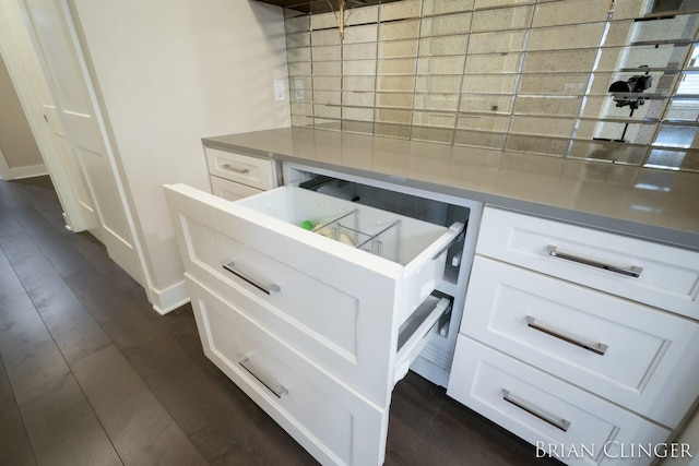 kitchen with tasteful backsplash, white cabinetry, dark wood-type flooring, and stainless steel counters