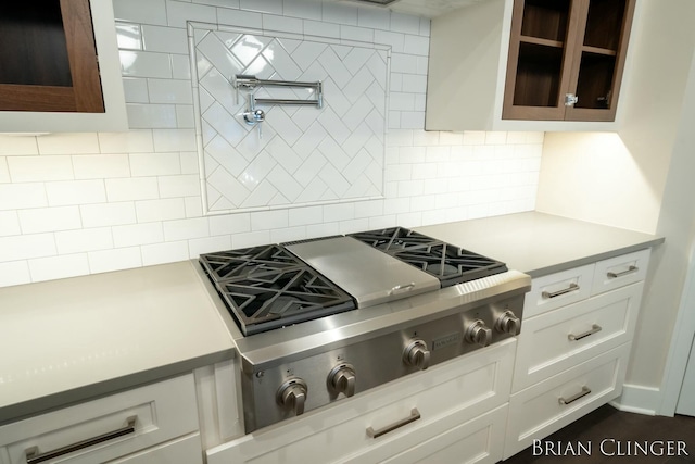 kitchen with tasteful backsplash, stainless steel gas cooktop, and white cabinets