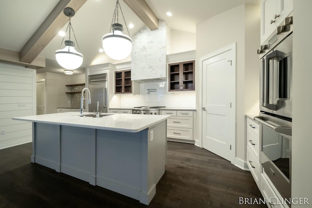 kitchen with pendant lighting, white cabinetry, vaulted ceiling with beams, a kitchen island with sink, and stainless steel appliances