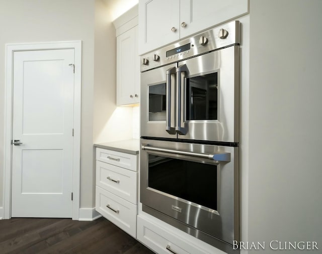 kitchen with dark hardwood / wood-style flooring, white cabinets, and double oven