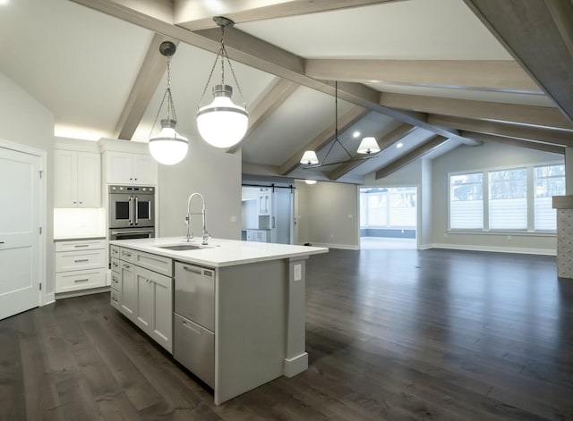 kitchen featuring lofted ceiling with beams, an island with sink, a barn door, and decorative light fixtures