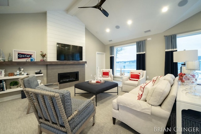 carpeted living room featuring ceiling fan, vaulted ceiling with beams, and a fireplace