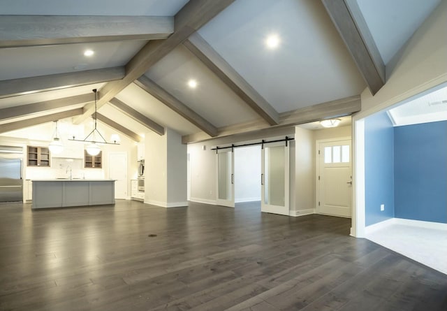 unfurnished living room featuring dark wood-type flooring, a barn door, sink, and vaulted ceiling with beams