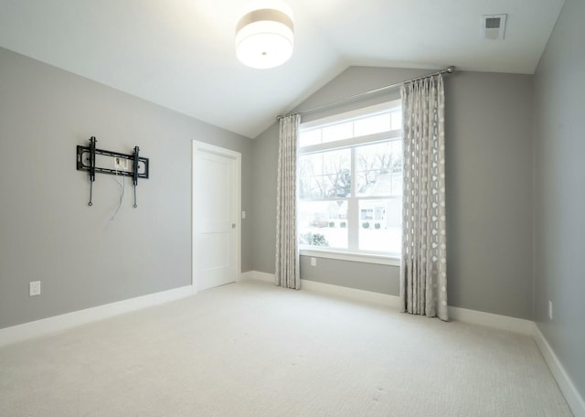 carpeted spare room with vaulted ceiling