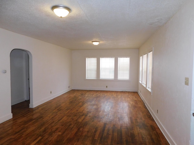 unfurnished room with dark wood-type flooring and a textured ceiling