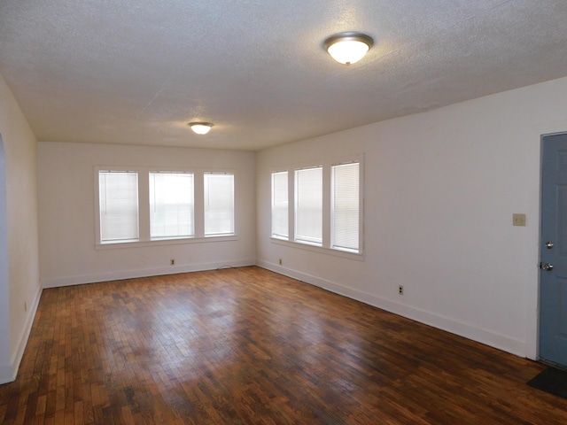 spare room featuring a textured ceiling and dark wood-type flooring