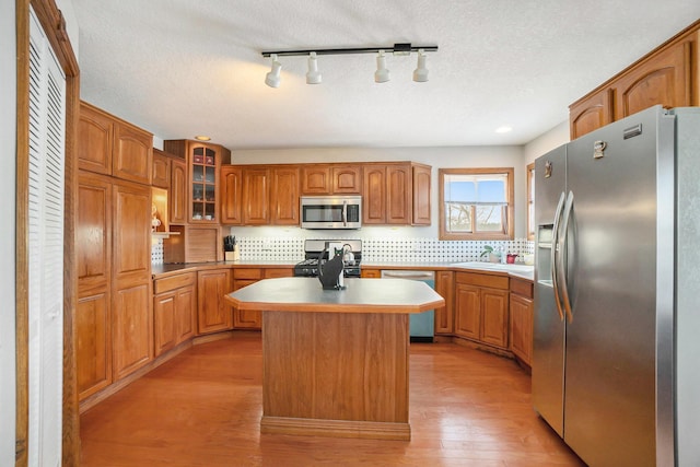 kitchen featuring a textured ceiling, stainless steel appliances, light hardwood / wood-style flooring, and a kitchen island