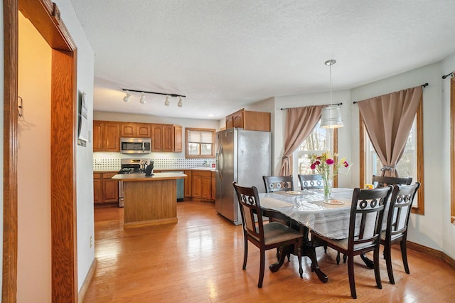 dining space featuring a textured ceiling, light hardwood / wood-style flooring, and rail lighting