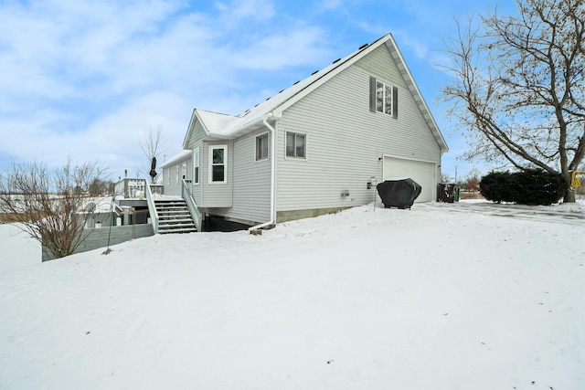 snow covered rear of property featuring a deck and a garage