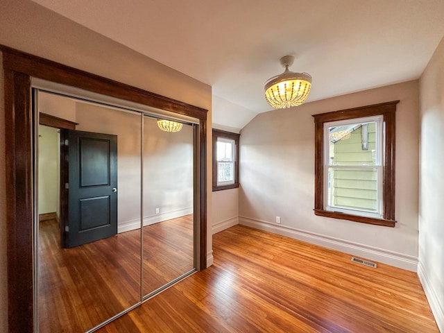 unfurnished bedroom featuring hardwood / wood-style floors, a closet, and vaulted ceiling