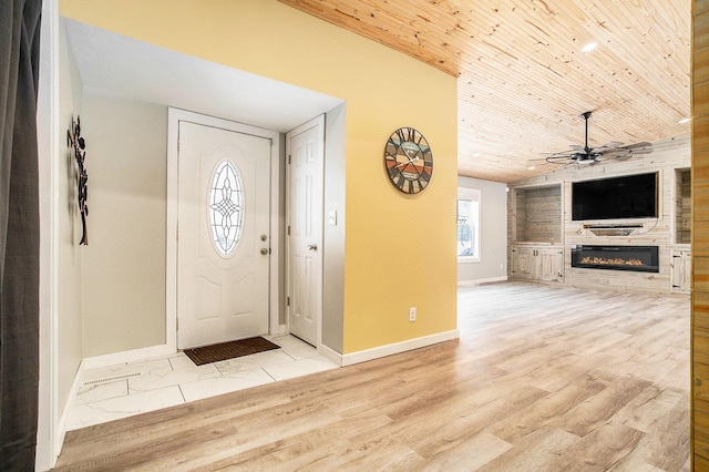 entrance foyer featuring a large fireplace, baseboards, a ceiling fan, wood ceiling, and wood finished floors