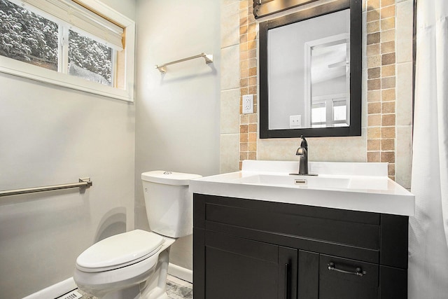 bathroom with toilet, a healthy amount of sunlight, baseboards, and vanity