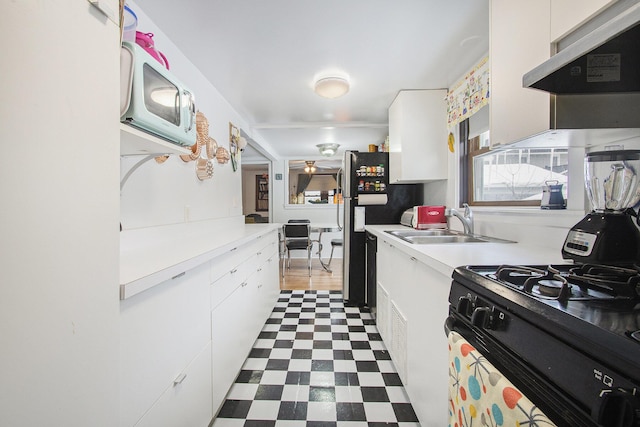 kitchen with a healthy amount of sunlight, sink, black gas range, and white cabinets