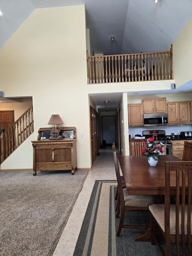 dining room with high vaulted ceiling and light carpet