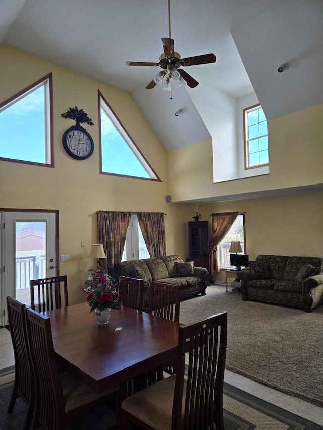 carpeted dining area with ceiling fan and high vaulted ceiling