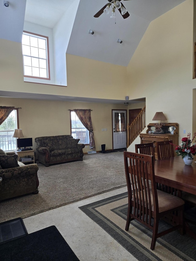 carpeted dining area featuring ceiling fan and high vaulted ceiling