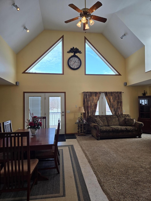 carpeted dining space featuring ceiling fan and high vaulted ceiling