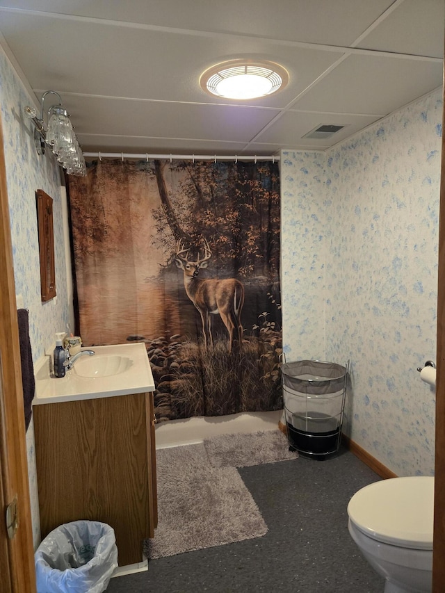 bathroom with toilet, a paneled ceiling, walk in shower, and vanity