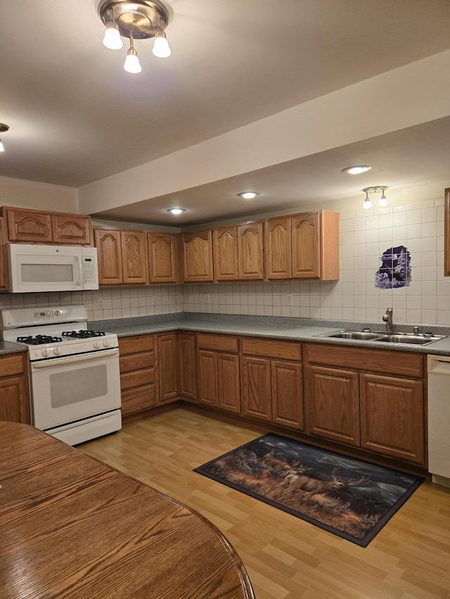 kitchen featuring light wood-type flooring, backsplash, sink, and white appliances