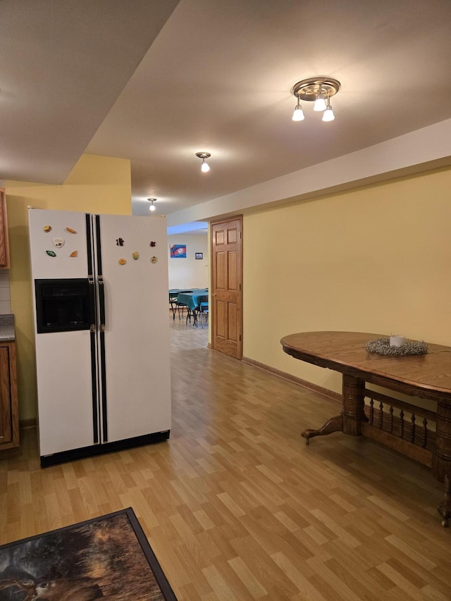 kitchen with white fridge with ice dispenser and light hardwood / wood-style flooring